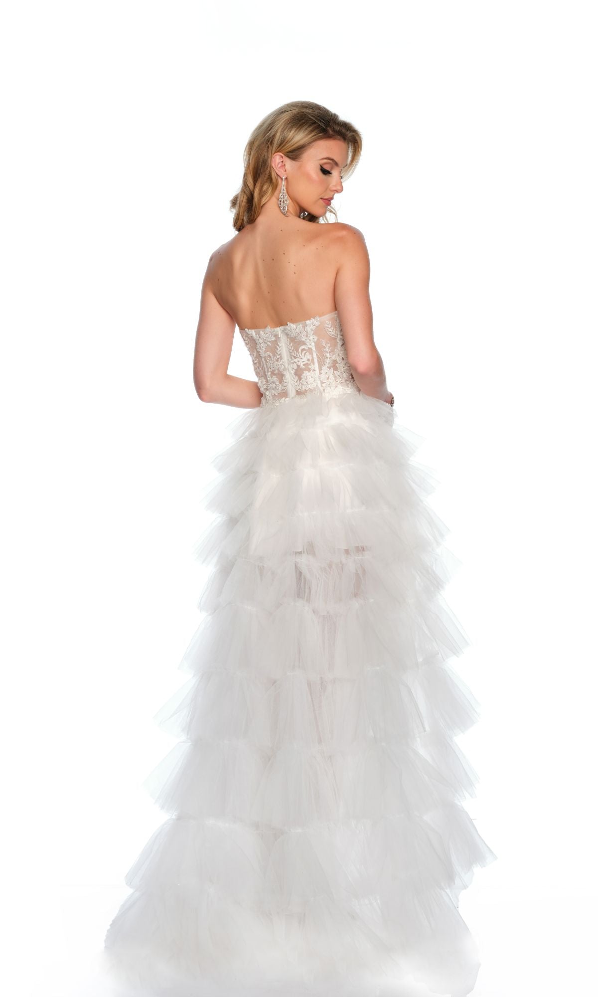 A woman models the Long Formal Dress 11651 by Dave and Johnny, featuring a strapless lace corset bodice and ruffle layered tulle skirt, shown from the back against a white background.